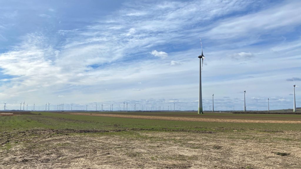 Windräder über abgeernteten Feldern im nördlichen Burgenland unter einem hohen Wolkenhimmel