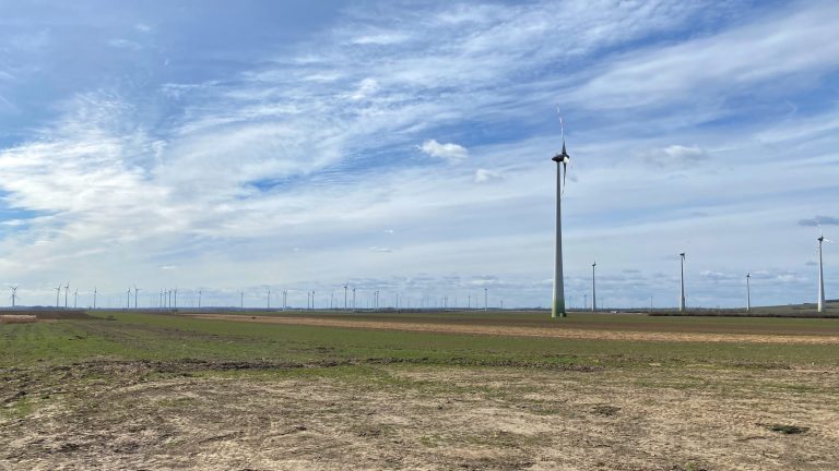 Windräder über abgeernteten Feldern im nördlichen Burgenland unter einem hohen Wolkenhimmel